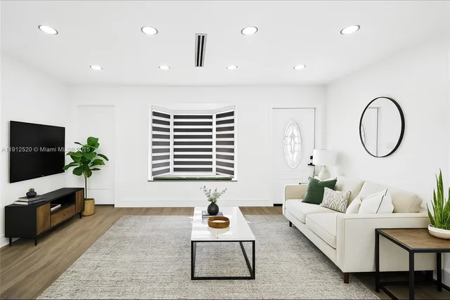 a living room with furniture a flat screen tv and a window