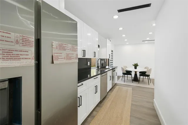 a kitchen with stainless steel appliances a refrigerator and a wooden floor