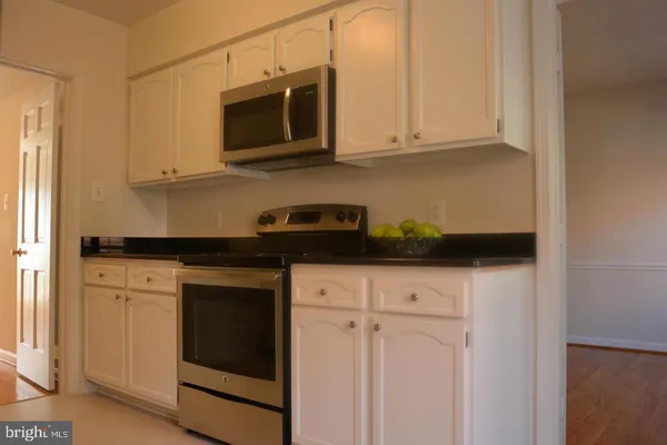 a kitchen with stainless steel appliances granite countertop white cabinets granite counter tops and a wooden floors