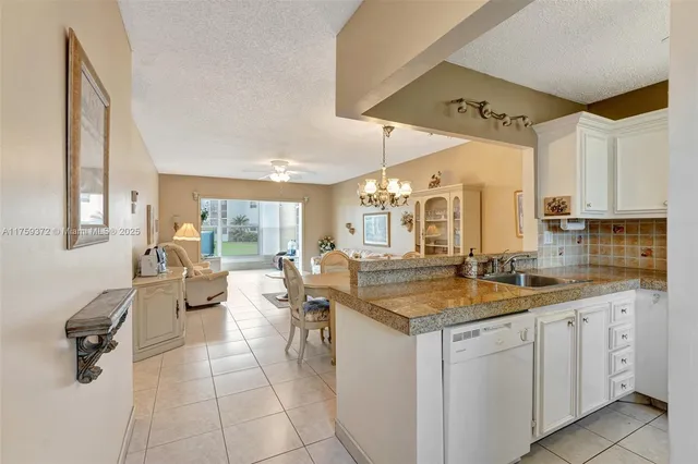 a hall with kitchen island granite countertop a sink and white cabinets
