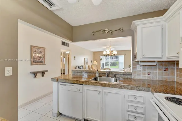 a kitchen with granite countertop white cabinets and white appliances