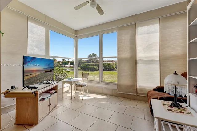a living room with furniture a flat screen tv and floor to ceiling window