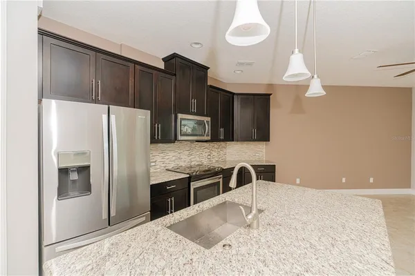 a kitchen with stainless steel appliances granite countertop a refrigerator a stove and a sink with wooden floor