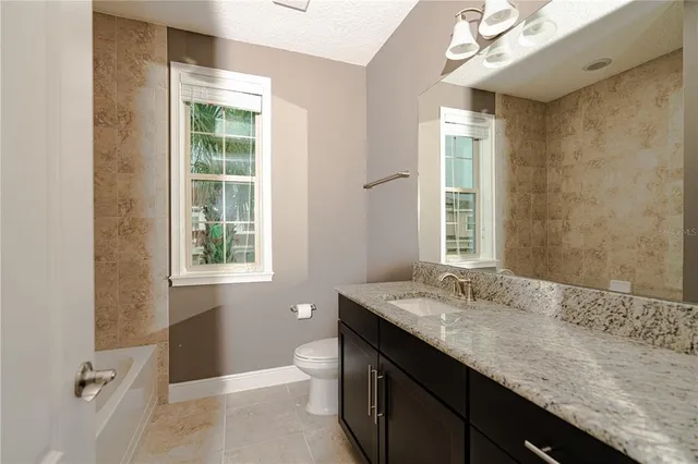 a bathroom with a granite countertop sink a toilet and shower