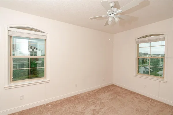 an empty room with a window and a fan