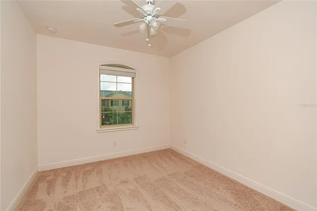 an empty room with a window and a fan