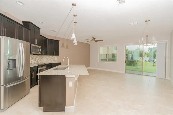 a kitchen with stainless steel appliances granite countertop a refrigerator a sink a stove and a refrigerator with wooden floor