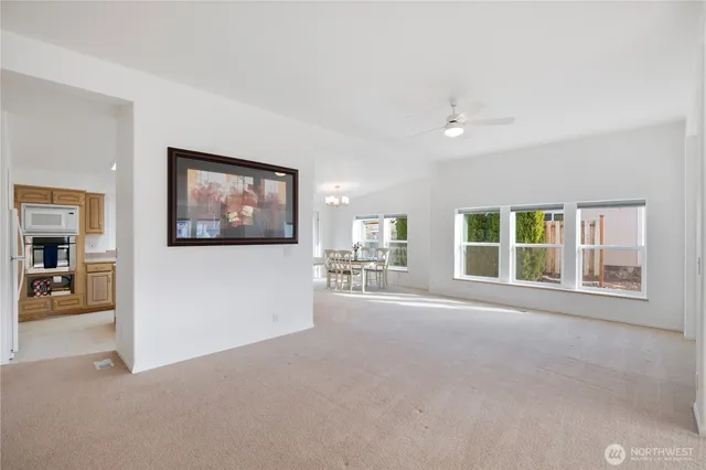 a view of an empty room with a window and a kitchen