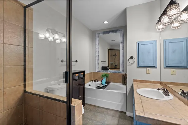 a bathroom with a granite countertop sink a bathtub and a mirror