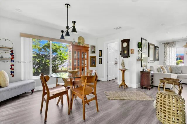 a kitchen with stainless steel appliances a refrigerator a stove a dining table and chairs with wooden floor