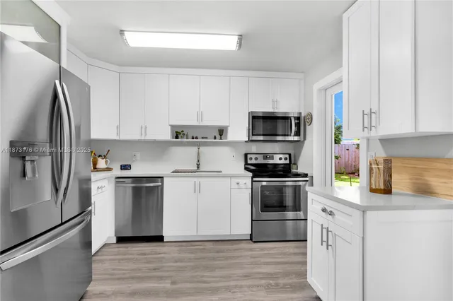 a kitchen with cabinets stainless steel appliances and wooden floor