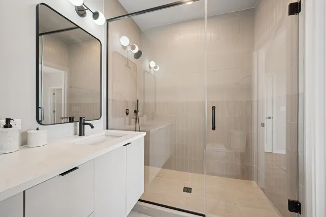 a bathroom with a shower sink vanity and mirror