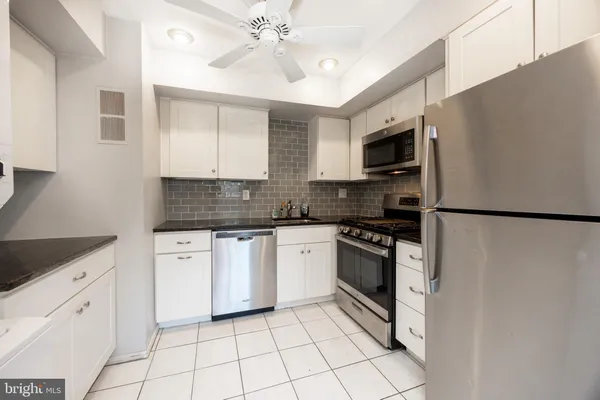 a kitchen with white cabinets and appliances
