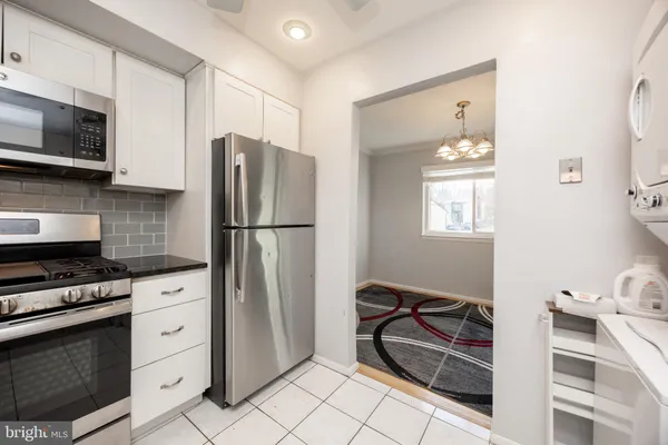 a kitchen with white cabinets and window
