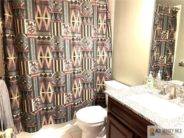 a bathroom with a granite countertop toilet a sink and a mirror