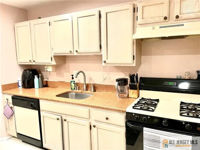a kitchen with kitchen island a sink a stove and white cabinets