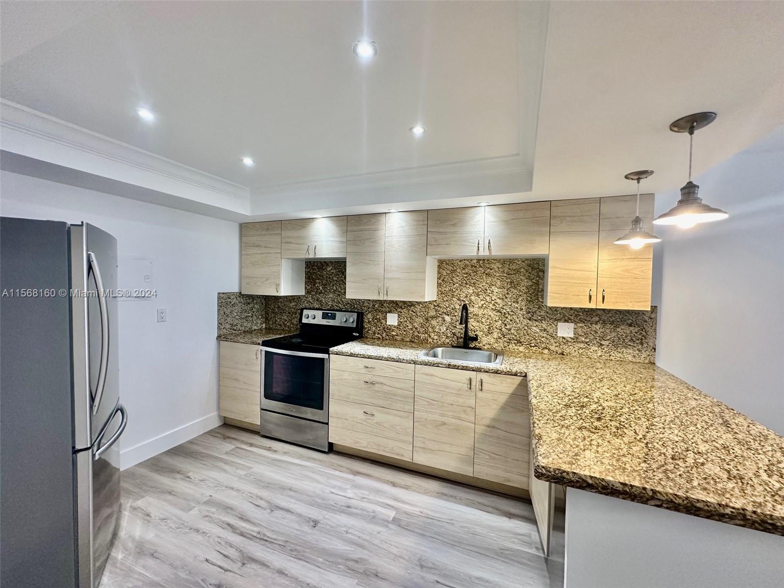 a large kitchen with stainless steel appliances kitchen island a large counter top and wooden floors