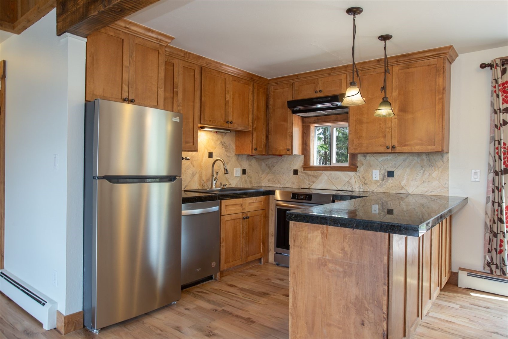 602 Ryan Gulch Road, Unit B Silverthorne, CO 80498 - Photo 1 of 34 Kitchen with stainless steel appliances, light wood flooring, and under cabinet range hood