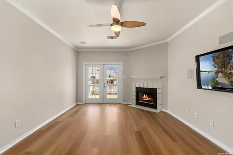 a view of an empty room with wooden floor fireplace and a window