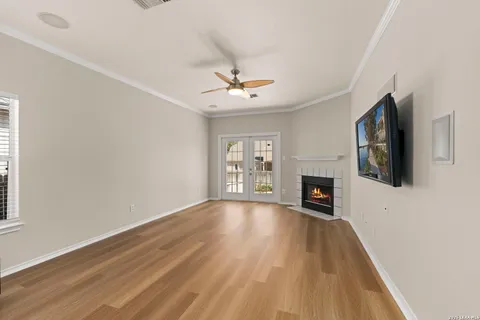 a view of a livingroom with a fireplace a ceiling fan and wooden floor