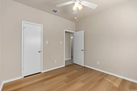 an empty room with wooden floor and a chandelier fan