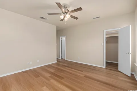 an empty room with wooden floor and ceiling fan