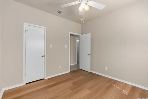 an empty room with wooden floor and a chandelier fan