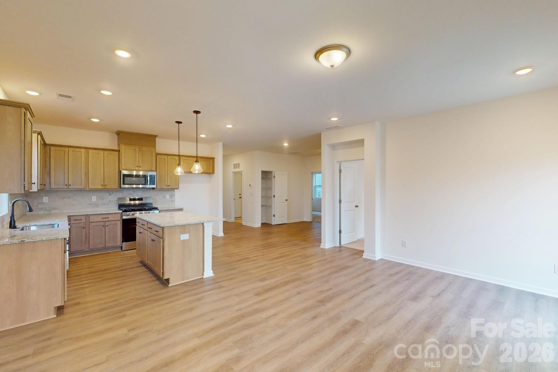 929 Barker Street Monroe, NC 28112 - Photo 14 of 26 a view of kitchen with kitchen island a sink wooden floor and a counter top space