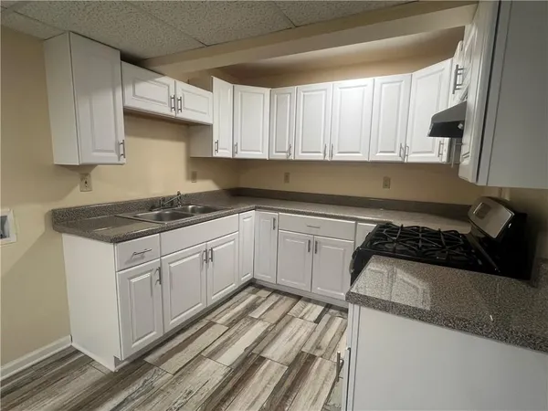 a kitchen with granite countertop a sink stove and cabinets