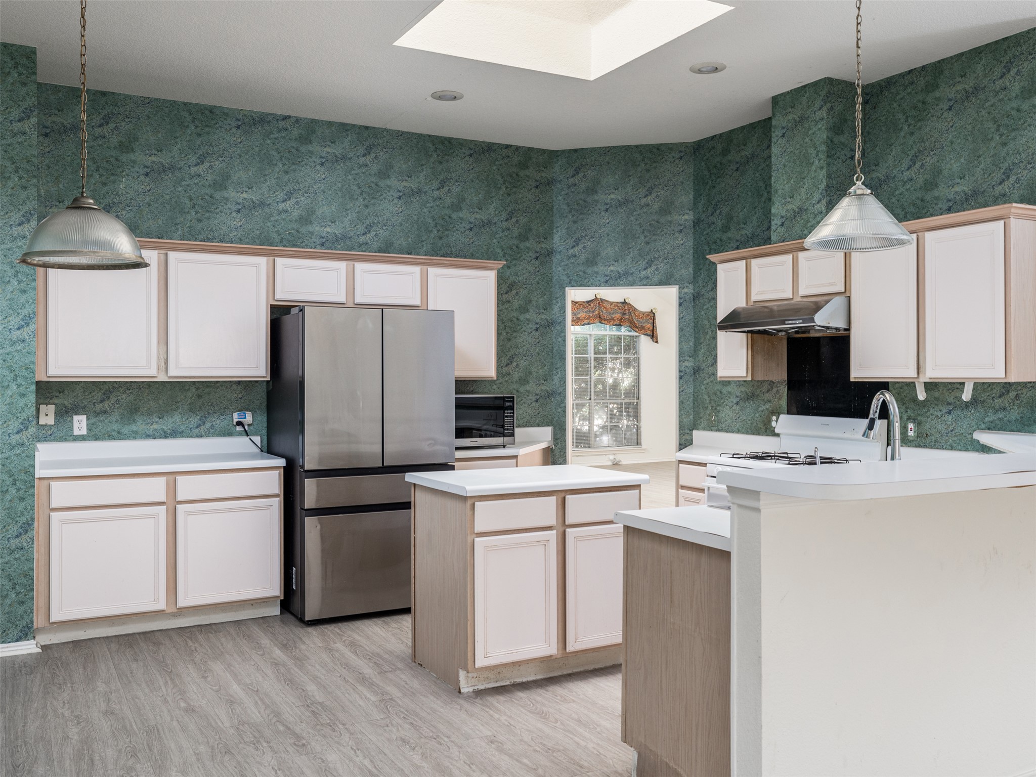 8537 Foxhound Trail Austin, TX 78729 - Photo 9 of 26 Kitchen featuring decorative light fixtures, stainless steel appliances, light countertops, wallpapered walls, and a peninsula