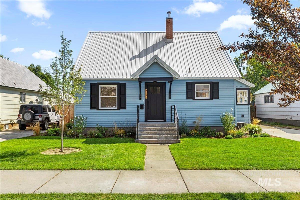 New england style home with a front lawn, a metal roof, and a chimney
