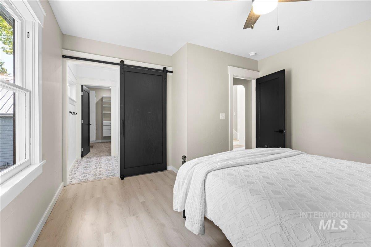 914 West 3rd Street Weiser, ID 83672 - Photo 24 of 49 Bedroom with light wood-type flooring, a barn door, a spacious closet, and a ceiling fan