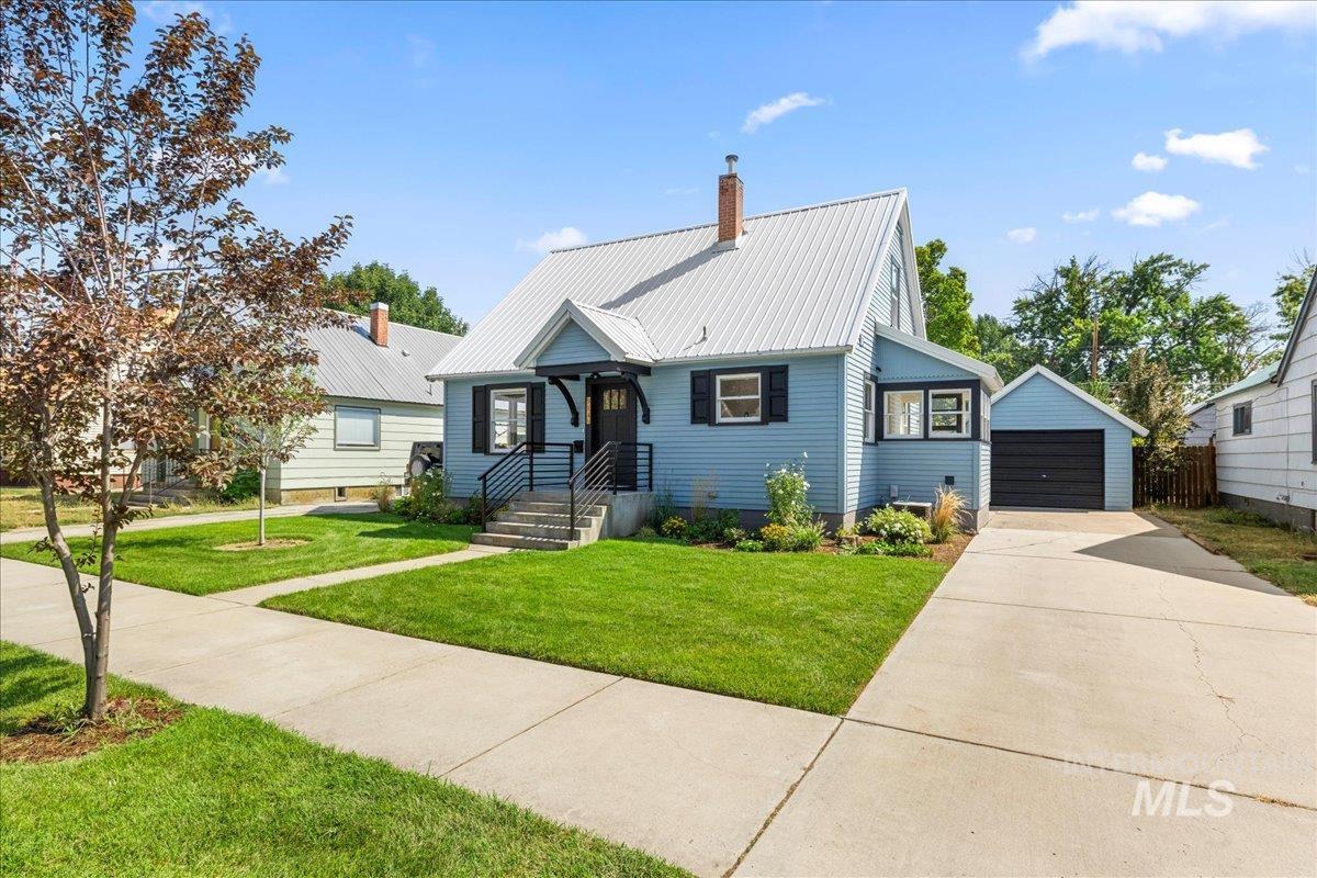 914 West 3rd Street Weiser, ID 83672 - Photo 3 of 49 View of front of house featuring an outdoor structure, a detached garage, a metal roof, a front lawn, and a chimney
