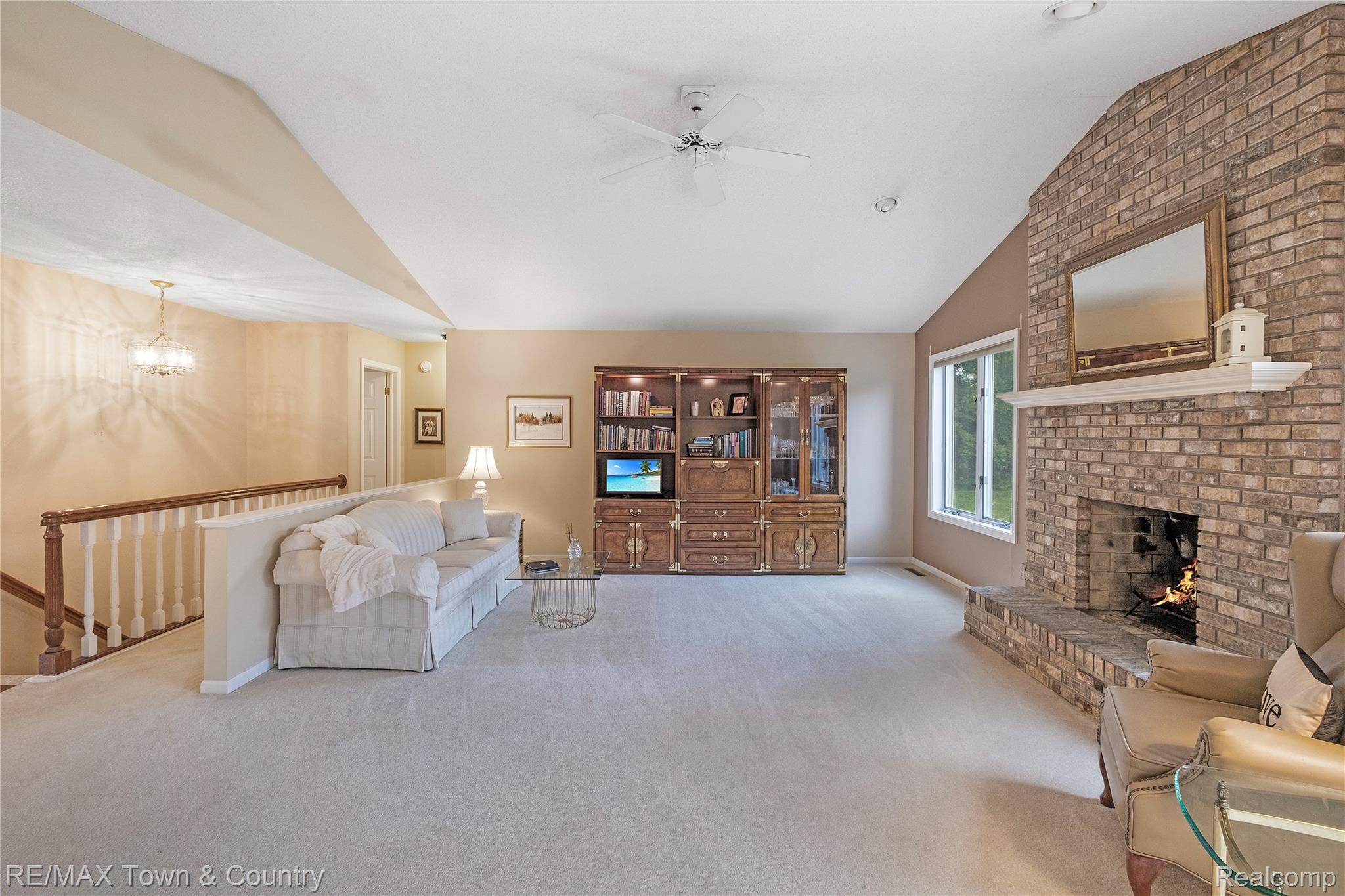 5464 North Seymour Road Flushing, MI 48433 - Photo 8 of 45 Vaulted ceiling with ceiling fan, brick fireplace with stone hearth, single window, and light-toned carpeting throughout
