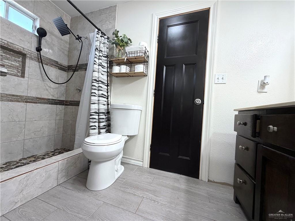 4204 Lott Road Donna, TX 78537 - Photo 11 of 28 Bathroom featuring a tiled shower with a niche, a dual-head shower system with a handheld sprayer, and a pebble-stone shower base
