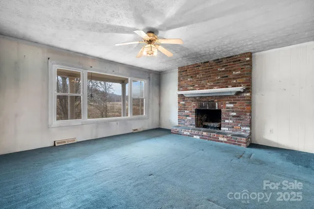 an empty room with windows fireplace and fan
