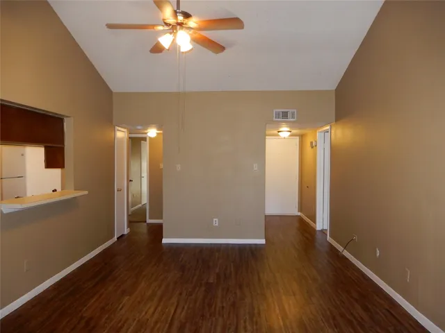 an empty room with wooden floor a ceiling fan and a fireplace