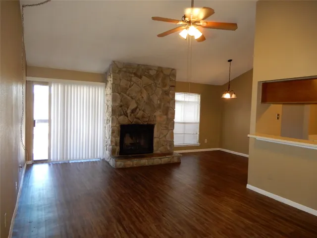 a view of an empty room with wooden floor fireplace and a window