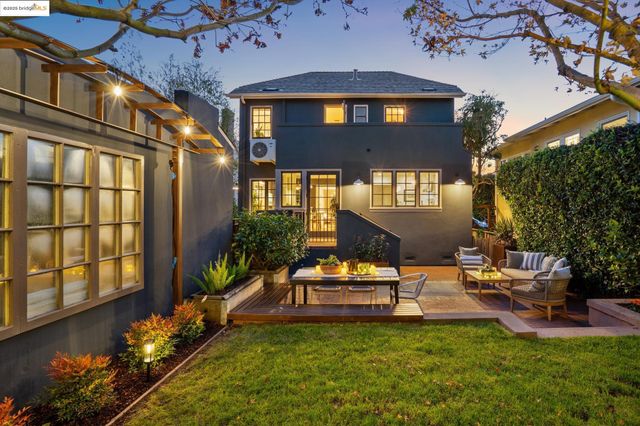 a view of a house with brick walls and a yard with plants and trees