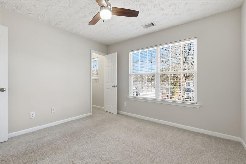 3570 Bogan Mill Road Northeast Buford, GA 30519 - Photo 21 of 31 an empty room with chandelier fan and windows