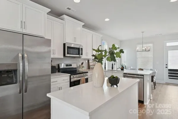 a kitchen with a refrigerator a oven a sink a dining table and chairs