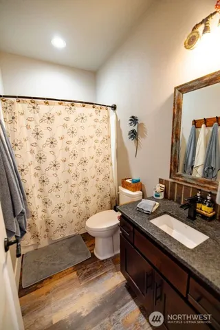 a bathroom with a granite countertop toilet sink and mirror