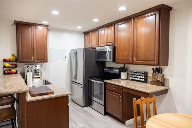 a kitchen with stainless steel appliances granite countertop a refrigerator a stove a sink and a microwave