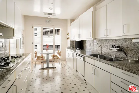 a kitchen with stainless steel appliances a stove a sink and white cabinets