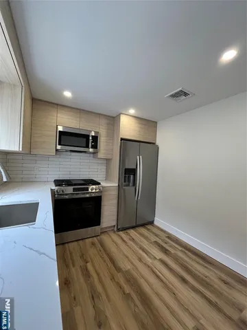a kitchen with granite countertop a refrigerator and a stove top oven