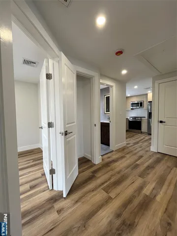 a view of a hallway with wooden floor and a bathroom