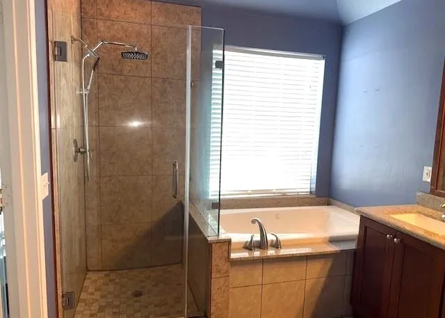 a bathroom with a granite countertop sink and a bathtub
