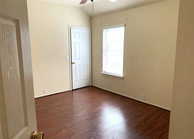 an empty room with wooden floor and windows