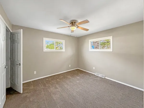 an empty room with windows and fan