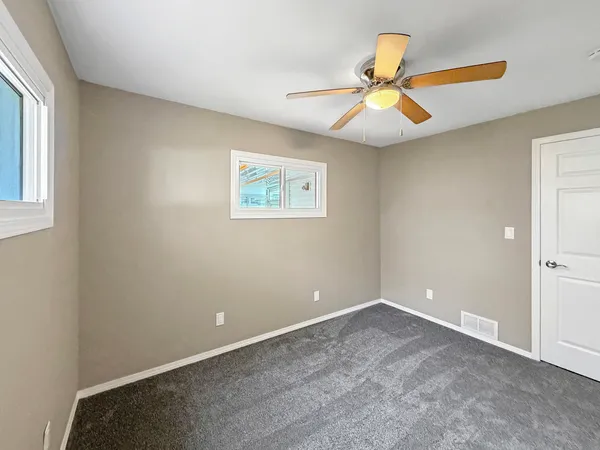 an empty room with window and ceiling fan